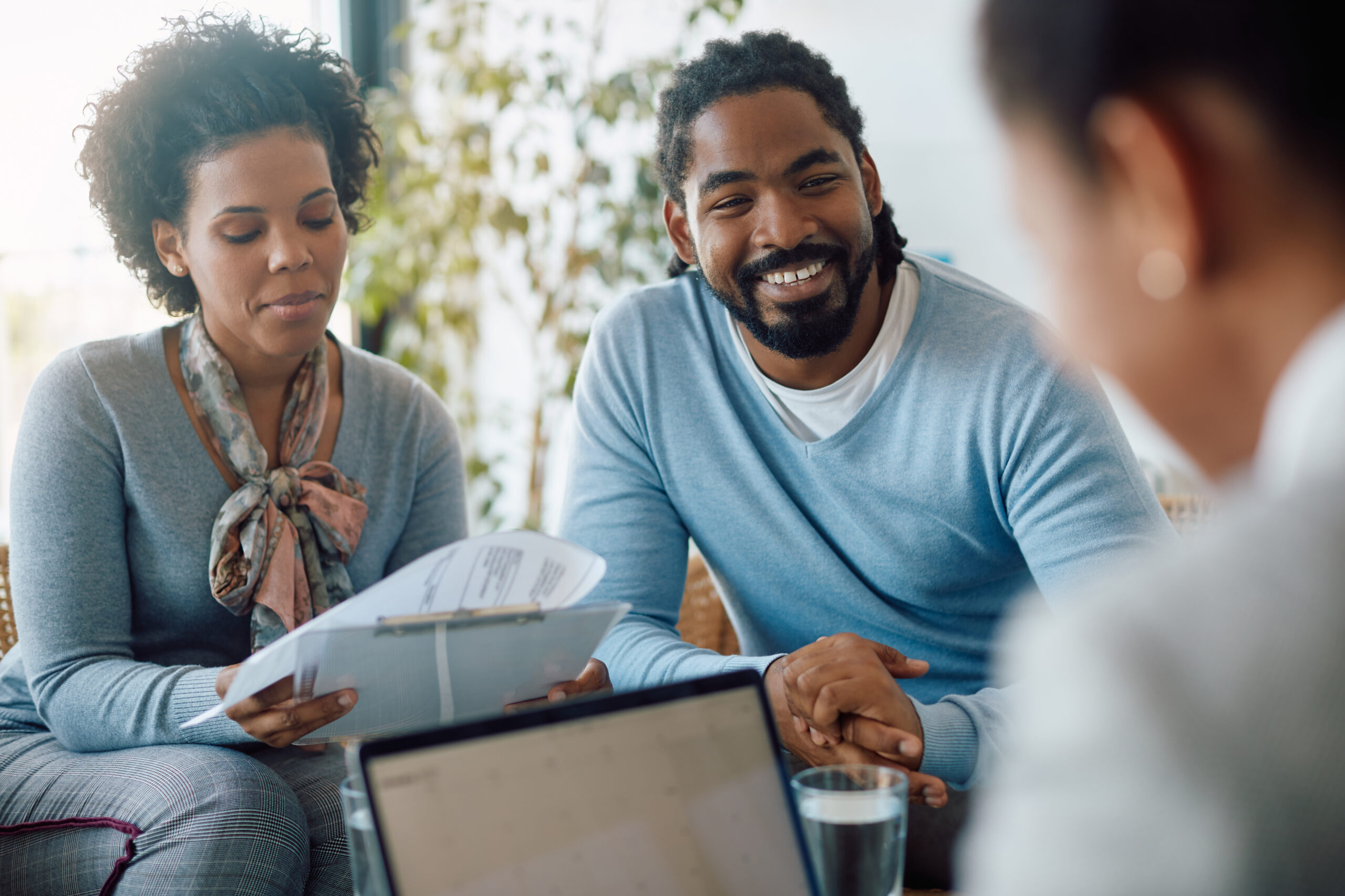 Happy black couple goes through paperwork while being on meeting with financial advisor.