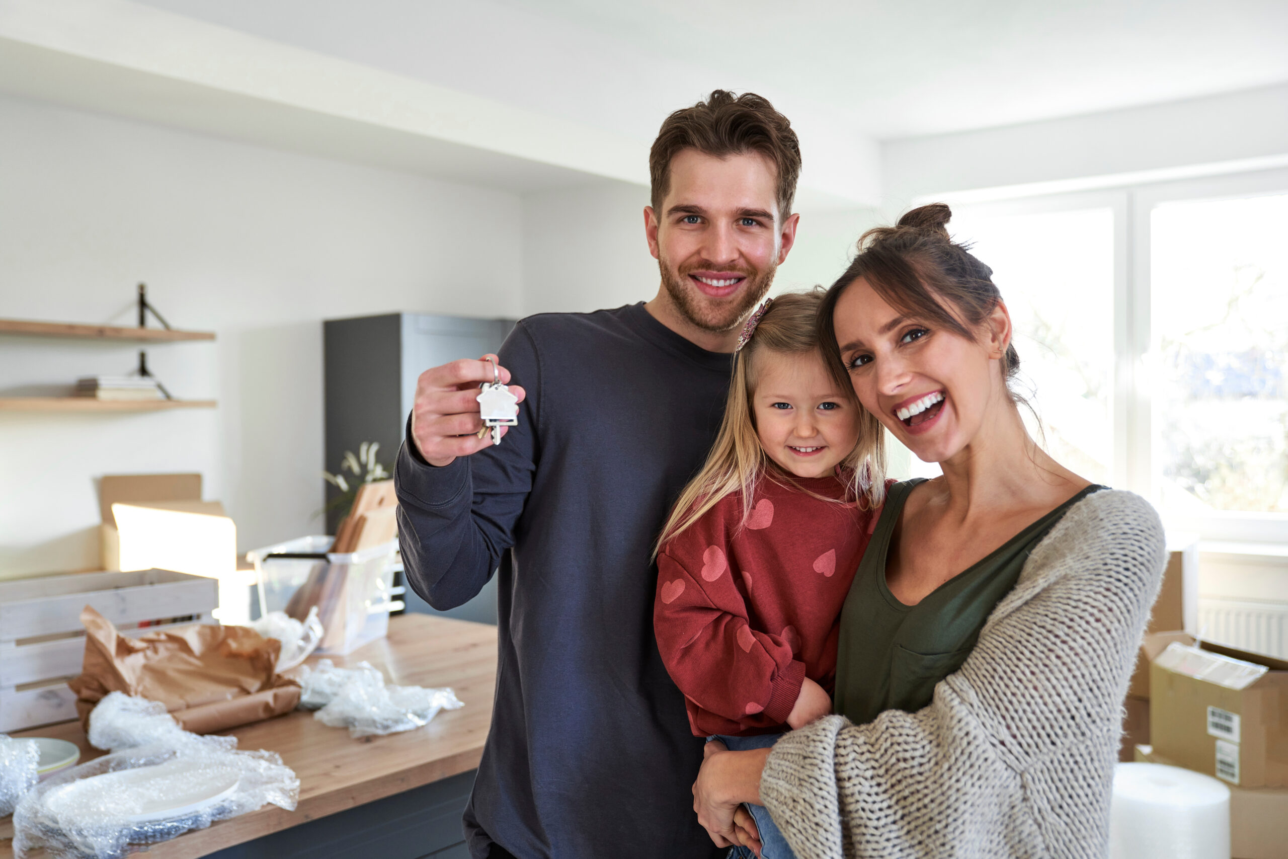 Portrait of happy caucasian family with daughter in a new apartment
